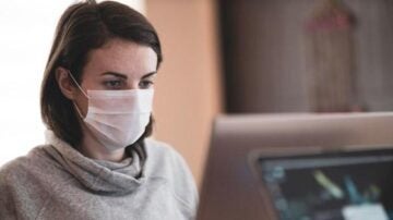 a woman on the computer wearing a covid mask